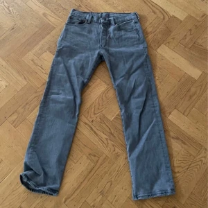 Levi's 501 grå jeans W31 L30 - Klassiska Levi's 501 jeans i en snygg grå nyans. Rak passform med normal midja. Tillverkade i slitstarkt jeanstyg, perfekta för en avslappnad och tidlös stil. Ikonisk läderpatch bak i midjan och knappgylf. Bra skick lite använda.