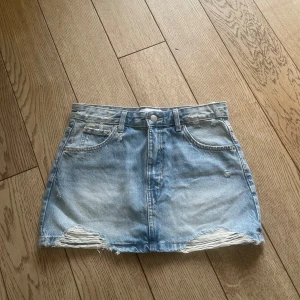 Ljusblå jeanskjol från Pull&Bear - Säljer en ljusblå jeanskjol från Pull&Bear med slitna detaljer och fransad nederkant. Midjemått 39cm ❤️