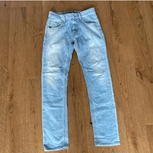 Ljusblå raka jeans tigerofsweden  - Säljer ett par ljusblå jeans med klassisk femficksdesign och raka ben. Jeansen har normal passform och är tillverkade i denim. Perfekta för en avslappnad och stilren look.