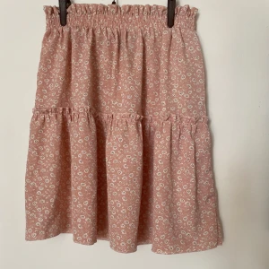 Rosa blommig volangkjol från shein - Supersöt rosa kortkjol från shein med små vita blommor och volangdetaljer. Använd 1 gång så den är i bra skick, storlek M men passar xs-m🩷