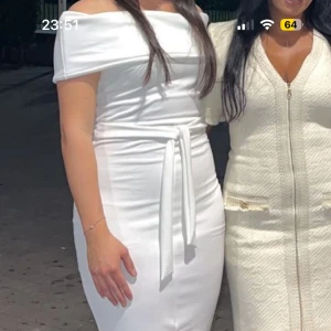 Vit offshoulder klänning med knyt - Snygg vit klänning med offshoulder och knyt i midjan. Figurnära passform, slits framtill och axelbandslös design. Perfekt för dig som vill sticka ut med en stilren look.