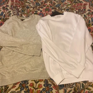 Grå och vit sweatshirt H&M S - Två stilrena sweatshirts i storlek S från H&M. En är ljusgrå och den andra är helvit, båda med relaxed fit och klassisk rund hals. Perfekta för en chill look och funkar till allt. Mjukt material och långa ärmar för extra komfort.