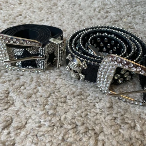 2 y2k bälten - Säljer två svarta Y2K bälten då dem aldrig kommit till användning🩷 Nyskick🩷 Ett bälte har stjärnmönster i svart och silver, det andra har rhinestones med döskallar🩷Det med döskallar är ca 95cm långt och det med stjärnor är ca 105cm🩷