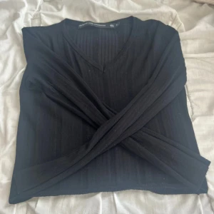 Svart ribbad tröja från The Black Label - Svart långärmad tröja från The Black Label Collection i storlek S. Tröjan har ribbad struktur, v-ringning och är i en slim passform. Perfekt att styla med jeans eller kjol för en clean look. Finns även en i XS om man vill ha det. 