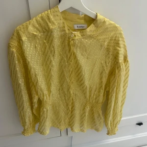Gul blus med glittriga detaljer från rodebjer - Snygg blus med fina detaljer. Den har resår i midjan som gör att den formar sig snyggt. Fina glittriga detaljer som gör de festlig. Perfekt i sommar. 