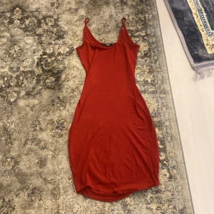 Röd ribbad klänning från Bik Bok XS - Säljer en tight, ribbad röd klänning från Bik Bok i storlek XS. Klänningen är ärmlös med smala axelband och har en kroppsnära passform som framhäver figuren. Perfekt för dig som gillar en enkel men snygg look.