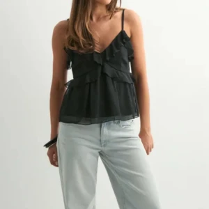 Svart volangig linnetopp - Supersöt svart linnetopp med tunna axelband och flera lager volanger framtill. Nypris 299, pris kan diskuteras!🥰