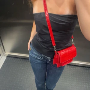 Svart bandeau tubtopp - Säljer en svart bandeau tubtopp med stilren och enkel design. Toppen är axelbandslös och sitter tight mot kroppen, perfekt för dig som gillar minimalistisk stil. Passar snyggt till både jeans och kjol.