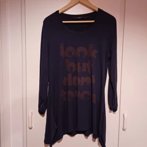 Tröja/kofta  - Snygg mörkblå långärmad tröja från One Two med trycket 'look but don't touch' framtill. Tröjan har rund halsringning, lite längre modell med asymmetrisk nederkant och knytdetalj vid ärmsluten. Perfekt för en chill och avslappnad stil.
