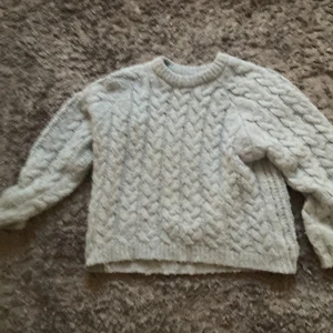 Ljusblå stickad tröja från Zara - Supermysig ljusblå stickad tröja från Zara med flätstickat mönster både fram och på ärmarna. Tröjan har rund halsringning och långa ärmar, perfekt för kyliga dagar. Passar dig som gillar en klassisk och chill stil.lite nopprig 😊
