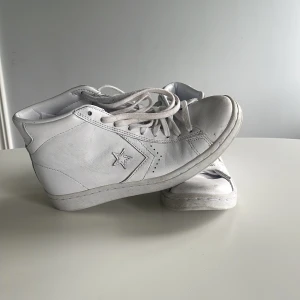 Vita Converse sneakers i skinn - Snygga vita Converse sneakers i skinn med klassisk stjärnlogga på sidan. Modellen är mid cut med snörning och rund tå. Perfekta för dig som gillar en clean och stilren look. Passar till det mesta och är lätta att matcha. Kan hämtas upp i Huddinge annars står man för frakten själv 