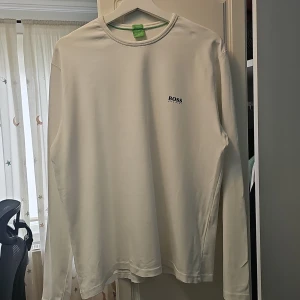 Vit långärmad tröja från BOSS - Säljer en stilren vit långärmad tröja från Boss 🔥 Perfekt för både vardag och fest ✨️            Tröjan är i bra skick och har en liten logga på bröstet, köpt i Boozt.                                                                 Passar perfekt till jeans eller chinos för en avslappnad look. xxl men ska passa medium till Large ✅️