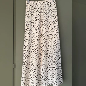 Prickig Långkjol  - Säljer en vit långkjol från Gina Tricot med svarta prickar. Passar perfekt in i kategorin polkadot som är sommarens design. Använd en gång på en skolavslutning. Kommer inte till användning. 