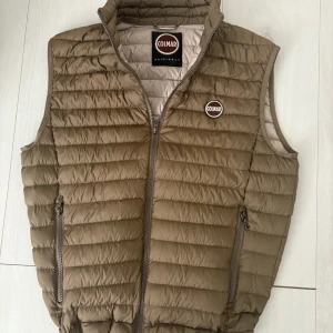 Colmar väst  - Snygg olivgrön dunväst från Colmar med quiltad design och dragkedja framtill. Västen har två fickor med dragkedja och en hög krage. Perfekt för lager-på-lager och har en stilren look med Colmar-logga på bröstet.