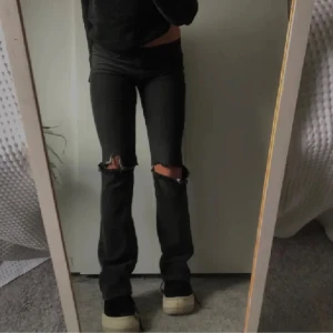 Svarta Levi’s  jeans  - Snygga svarta jeans med bootcut passform och slitna hål på båda knäna. Jeansen har låg midja och klassisk femficksdesign. Köpta på plick men har inte kommit till användning🤍