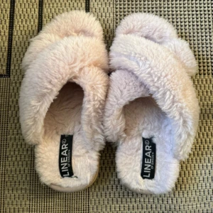 Fluffiga tofflor från Linear of Sweden - Supermjuka och fluffiga sandaler i ljusbeige från Linear of Sweden. De har korsade band och är helt täckta i mysig syntetpäls, perfekta för att chilla hemma eller mysa runt i. Snygg och trendig look för dig som gillar komfort och stil.