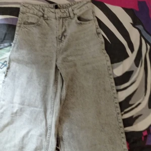 Gråa raka jeans från H&M, stl 30 - Säljer ett par gråa raka jeans från H&M i storlek 30. Jeansen har klassisk femficksdesign, bälteshällor och en snygg tvättad look. Perfekta för dig som gillar en avslappnad och stilren vibe.