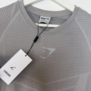 Gymshark Onyx V2 - Sitter snyggt och kroppsnära över bröst, axlar och armar – med en passform som både lyfter fram fysiken och känns bekväm.  ✅ Helt ny med tagg kvar. Klassisk grå färg – enkel att matcha och funkar till allt. Modellen är ofta slutsåld tack vare sin passform och höga kvalitet.
