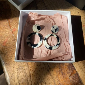 Svartvita statementörhängen i akryl - Coola örhängen i svart och vitt med marmorerat mönster. De är runda och tillverkade i akryl, perfekta för att ge din outfit en unik touch. 