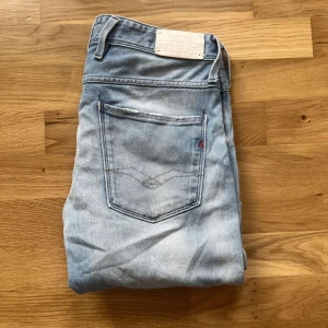 Replay Anbass jeans  - Säljer ett par ljusblå slim jeans från Replay med slitningar på knäna och klassiska femficksdetaljer. Jeansen har en snygg tvättad look och är tillverkade i stretchig denim för en bekväm passform. Perfekta för en avslappnad streetstil. Längd ca103cm! Man ser färgen på jeansen bättre på de sista 2 bilderna 