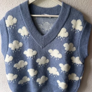 Blå stickad väst med molnmönster från Zara - Superfin blå stickad väst från Zara med vita moln och regndroppar över hela. Djup v-ringning och bred ribbad kant vid hals och ärm. 