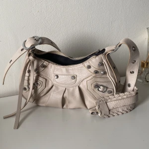 Beige axelväska i skinn med nitar - Cool beige axelväska i skinn med silvriga nitar och detaljer. 