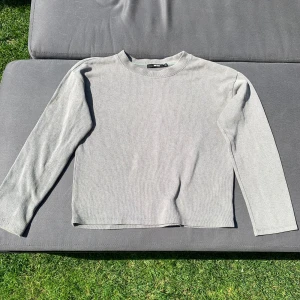Ljusgrå ribbad långärmad tröja - En stilren grågrön långärmad tröja från Bik Bok. Tröjan är ribbad och har en klassisk rund halsringning. Perfekt för lager-på-lager och enkel att matcha med olika outfits.