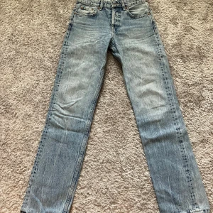 Ljusblå raka jeans från Zara - Säljer ett par ljusblå jeans från Zara i rak modell med medelhöj midja. Jeansen har klassisk femficksdesign, knappar framtill och råa, fransiga benslut för en cool vibe. Perfekta till sneakers eller boots.