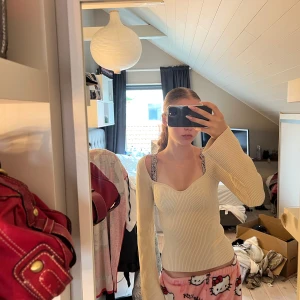 Ribbad ljusbeige långärmad topp - Supersnygg ribbad topp i ljusbeige med lång ärm och söt sweetheart-urringning. Figurnära passform och stretchigt material som sitter perfekt. Perfekt att styla med jeans eller kjol för en trendig look.