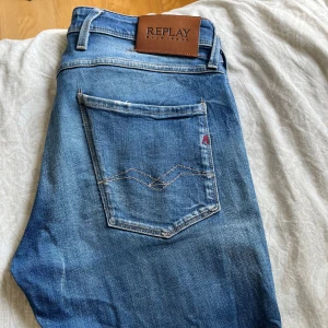 Blå jeans från Replay straight fit - Snygga blå jeans från Replay med klassisk femficksdesign och ljusa slitningar framtill. Jeansen har raka ben och normal passform, tillverkade i mjukt denimtyg. Perfekta för en avslappnad och stilren look.