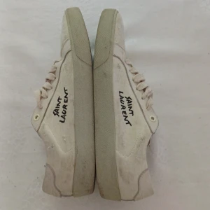 Krämvita saint laurent skor - Snygga creme färgade saint laurent sneakers, skick 7,5/10 småfläckar där framme och lutte missfärgningar från jeans som inte syns när dem är på, de små fläckarna borde gå att tvätta bort ganska enkelt, allmänt slitage på skon är väldigt litet, det kan man se genom tex sulan. Passar även 44