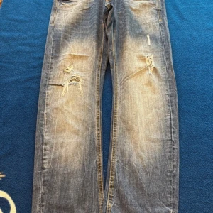 Blå slitna jeans från Cropp - Säljer ett par blå jeans från Cropp med slitningar och hål på framsidan. Jeansen har raka ben, klassiska bakfickor och en snygg tvättad look😍😍
