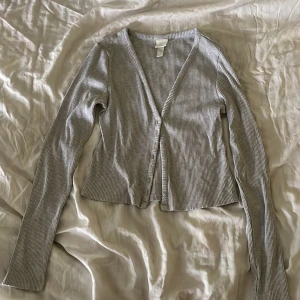 Grå ribbad kofta från H&M - ljusgrå ribbad kofta från H&M med stretchigt tyg, använd flera gånger men har inga synliga defekter 💕skriv vid frågor!