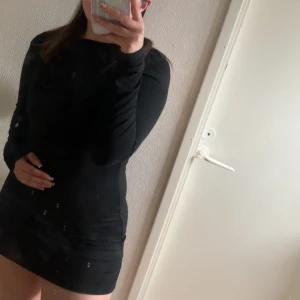 Svart tight långärmad kortklänning med öppen rygg  - säljer min svarta klänning med öppning i ryggen. Fin och bra passform, väldigt skönt material 