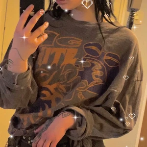 BDG brun/grå långärmad tröja med tryck  - Säljer en oversized brun långärmad t-shirt från BDG (Urban outfitters) med stort grafiskt tryck i orange, blå och grönt. Står ”big white lies” på. Tröjan har en avslappnad passform och är gjord i mjuk bomull. Perfekt för dig som gillar streetwear och unika prints. Fått av ett ex som aldrig använde den, knappt använd av mig! Färg: urtvättad brun/ varm grå