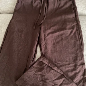 Bruna linnebyxor - Snygga bruna linnebyxor från Bik Bok med avslappnad passform och dragsko i midjan. Byxorna har raka ben och elastisk midja för extra komfort. Perfekta för en chill och stilren look. Medelhög midja, sitter till ankeln på mig som är 160cm