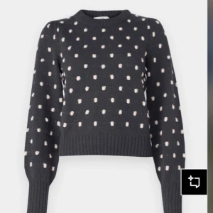 Mörkgrå stickad prickig tröja - Mysig mörkgrå stickad tröja med beige prickar över hela. Tröjan har rund halsringning, långa ärmar och ribbade muddar vid ärmslut och nederkant. Perfekt för dig som gillar en söt och trendig look. Ny pris är 429kr