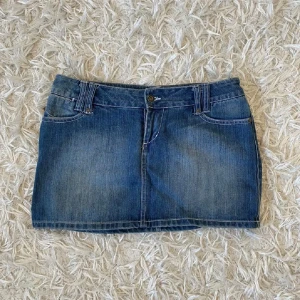 Blå jeanskjol från Only - Snygg blå jeanskjol från Only med klassisk femficksdesign, bälteshällor och coola bakfickor med dekorativa sömmar. Kjolen är kort och har en rak passform, perfekt till sneakers eller boots. Enkel knapp- och dragkedjestängning framtill.