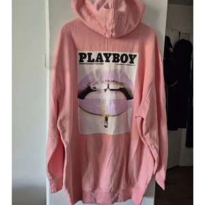 Rosa Playboy hoodie med tryck - Säljer en oversized rosa hoodie från Playboy med stor grafisk print på ryggen och liten logga framtill. Tröjan har huva, känguruficka och långa ärmar. Perfekt statement-plagg för dig som gillar streetwear och vill sticka ut.