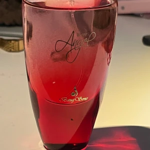 Be My Angel parfym röd flaska - Parfymflaska i en snygg röd färg med texten 'Be My Angel' och Beaug Sons-logga i guld. Flaskan har en elegant, avsmalnande form och är tillverkad i glas. Perfekt för dig som gillar stilrena och färgstarka detaljer på sminkbordet.