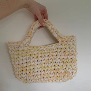 Handgjord virkad väska i gult och vitt - Super fin handgjord virkad väska . Väskan har mjuka handtag och är i ljusa toner av  gul och vit. Perfekt för att bära med sig allt man behöver till stan.