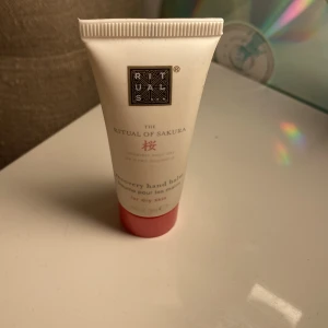 Rituals The Ritual of Sakura hand balm - Handbalsam från Rituals i serien The Ritual of Sakura. Tuben är vit med rosa botten och har en stilren design. Perfekt för torra händer och doftar fräscht av körsbärsblom. Smidig att ha med i väskan.