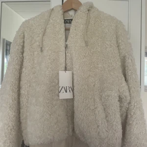 Gosig teddyjacka från Zara💕 - Supermjuk och fluffig vit teddyjacka från Zara med dragkedja och huva✨ Aldrig använd innan så den är helt ny!  Helt perfekt inför hösten eller sena sommarkvällar🩷 Även lite fodrad på insidan för lite extra värme!!