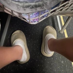 Yeezy slides - Säljer ett par trendiga beige slides i syntetmaterial. De har öppen tå och platt sula, perfekta för en avslappnad och chill stil. Passar lika bra till shorts som till mjukisbyxor.