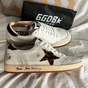 Golden goose Ballstar leopardstjärna - Snygga GGDB Ballstar sneakers i vitt skinn med beige sula och svart häl. Ikonisk stjärna i leopardmönstrad päls på sidan och handskriven text på sulan. Perforerad tå och detaljer i mocka framtill. Perfekta för dig som vill sticka ut med coola detaljer. OBS lnte 0rglnal!