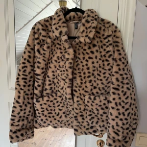 Leopardmönstrad pälsjacka H&M  - Säljer en fluffig och trendig pälsjacka från H&M Divided i storlek M. Jackan är beige med svart leopardmönster, har stora fickor framtill och stängs med tryckknappar. Perfekt statement-plagg för dig som vill sticka ut.