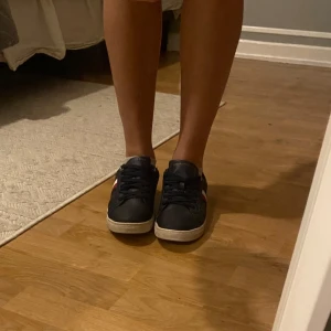 Marinblå sneakers från Tommy Hilfiger - Snygga marinblå sneakers från Tommy Hilfiger med klassiska ränder i vitt, rött och blått på sidan. 