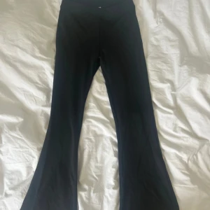 Svarta bootcut leggings från Gina Tricot - Svarta leggings från Gina Tricot med bootcut modell. Mjukt och stretchigt material som sitter skönt och ger en snygg siluett. Perfekta till sneakers eller boots för en chill och trendig look.