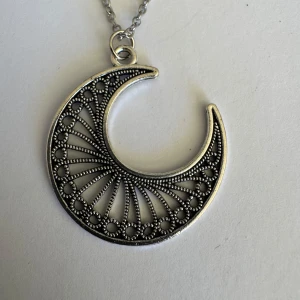 Halsband med silverfärgad månpendel - Min 5åriga dotters hobby att göra egna smycken. Så detta har hon gjort . Inget är äkta guld/silver.  Önskar man exakta mått på något så är det bara att skriva . Halsbanden är 45cm ungefär eller mer 