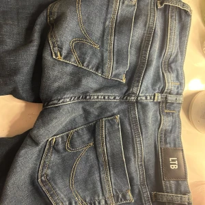 Blå bootcut jeans från LTB - Snygga blå jeans från LTB med bootcut-modell och låg midja. Klassisk femficksdesign, kontrastsömmar och mjukt denimtyg. Perfekta för dig som gillar en tidlös look med lite utsvängda ben.